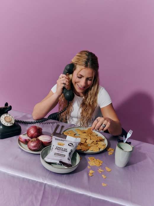 Ao telefone olhando o prato de chips